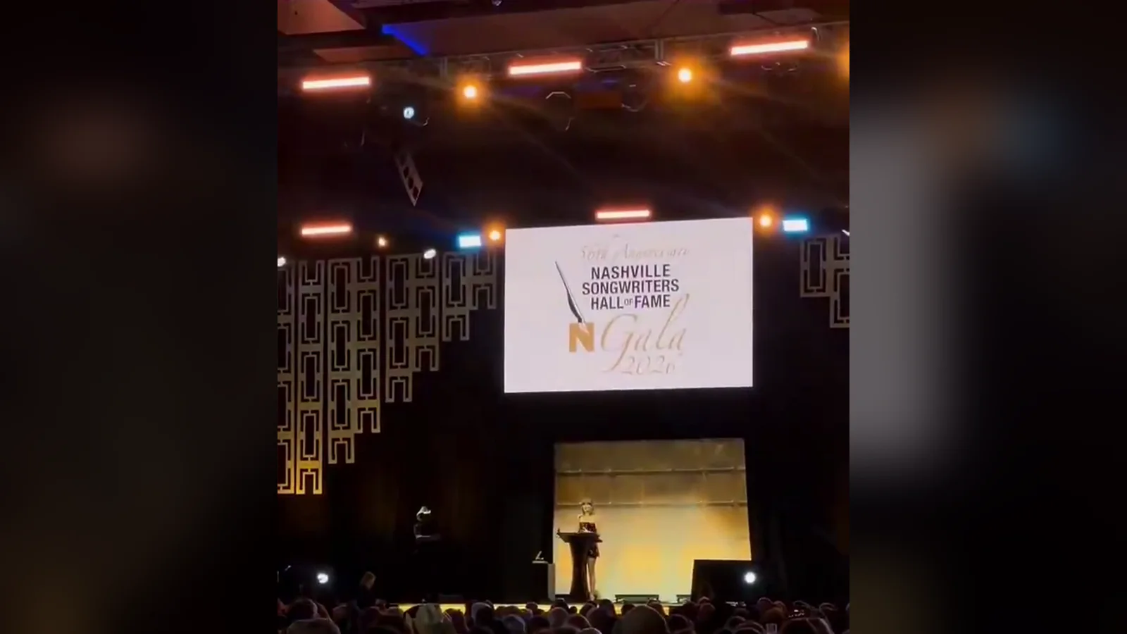 Toàn cảnh sân khấu gala Nashville Songwriters Hall of Fame 2026 tại Music City Center khi Taylor Swift đứng ở bục phát biểu
