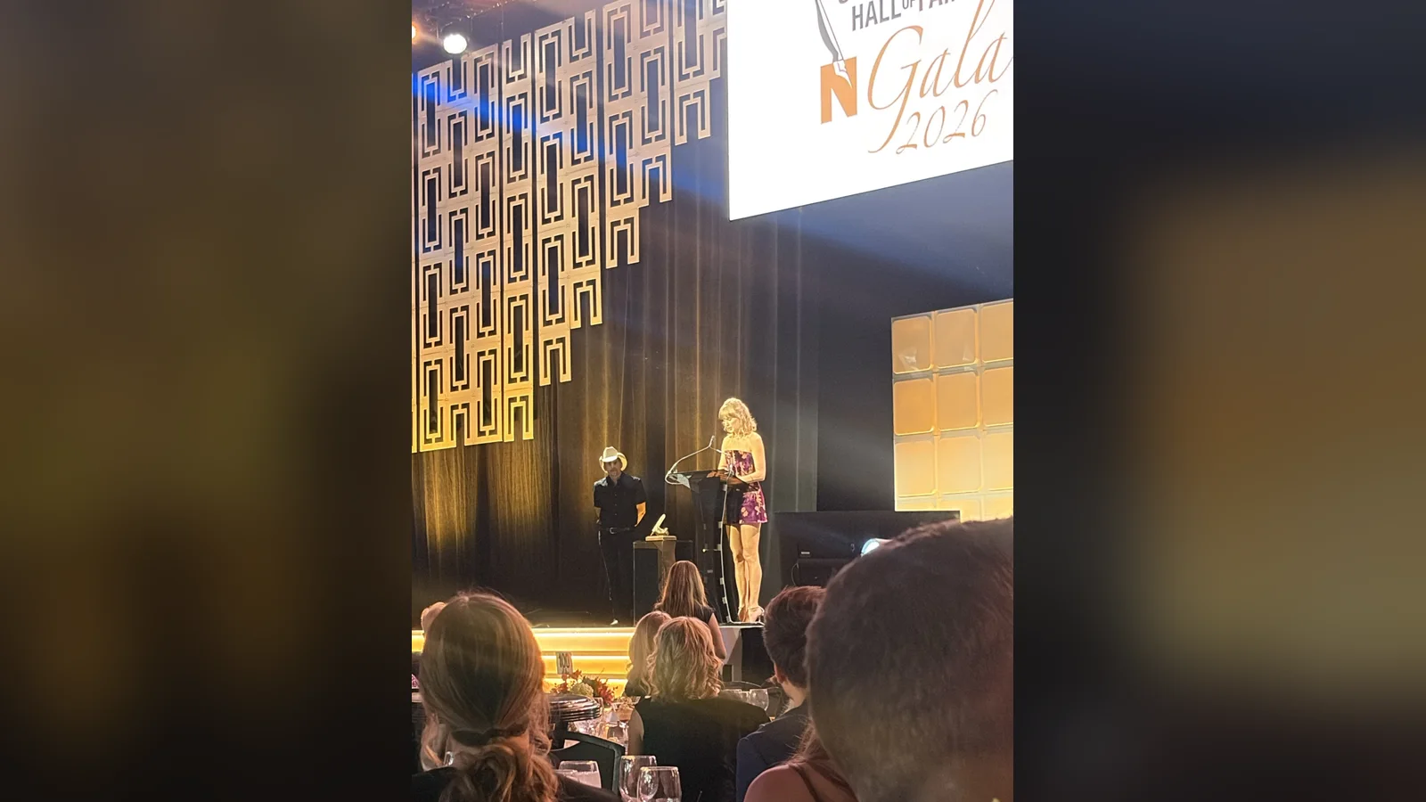Taylor Swift phát biểu tại gala Nashville Songwriters Hall of Fame 2026, Brad Paisley đội mũ cao bồi đứng cạnh