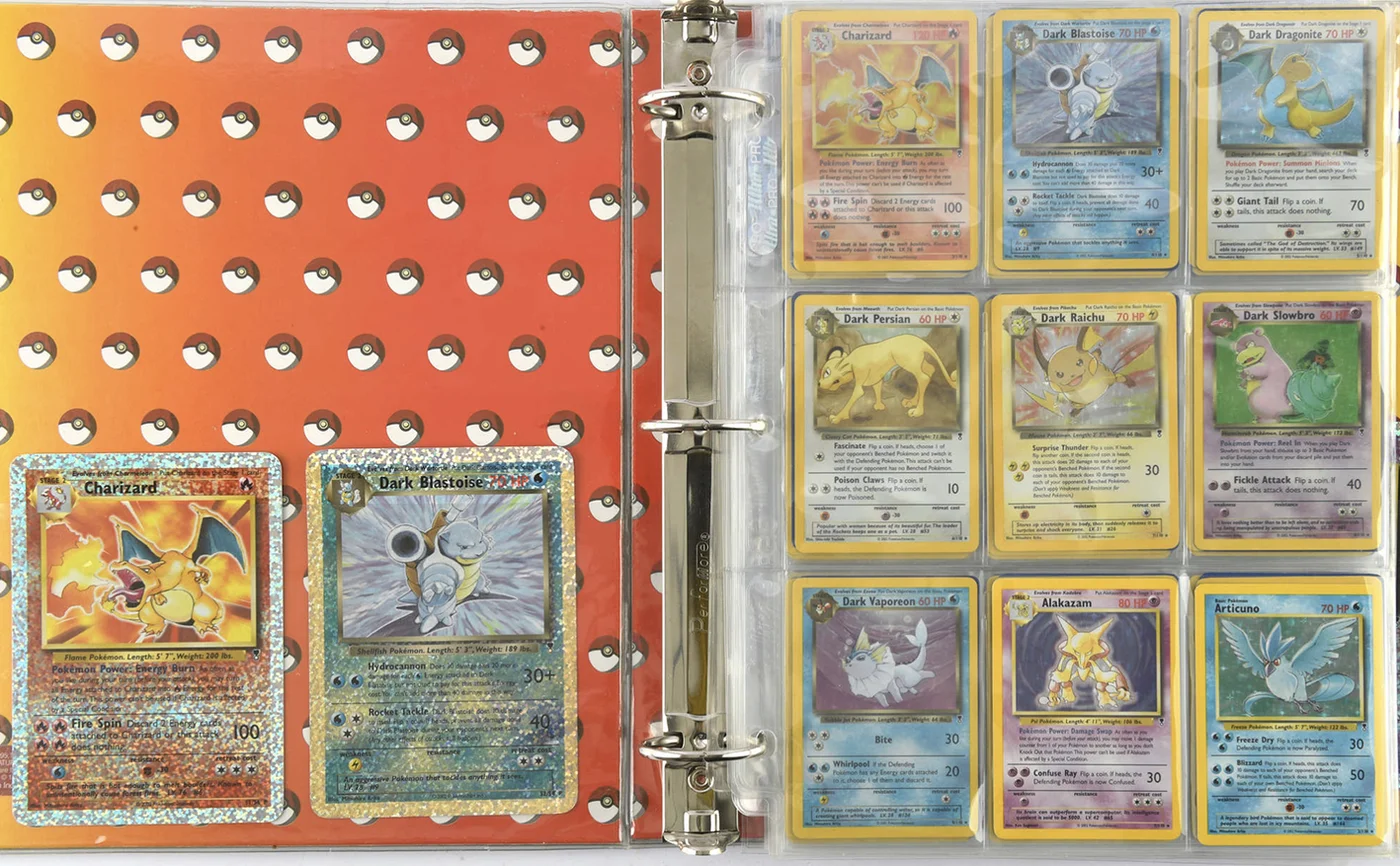Album thẻ Pokémon cổ mở ra, có lá Charizard và các thẻ Dark trong bộ sưu tập gác xép