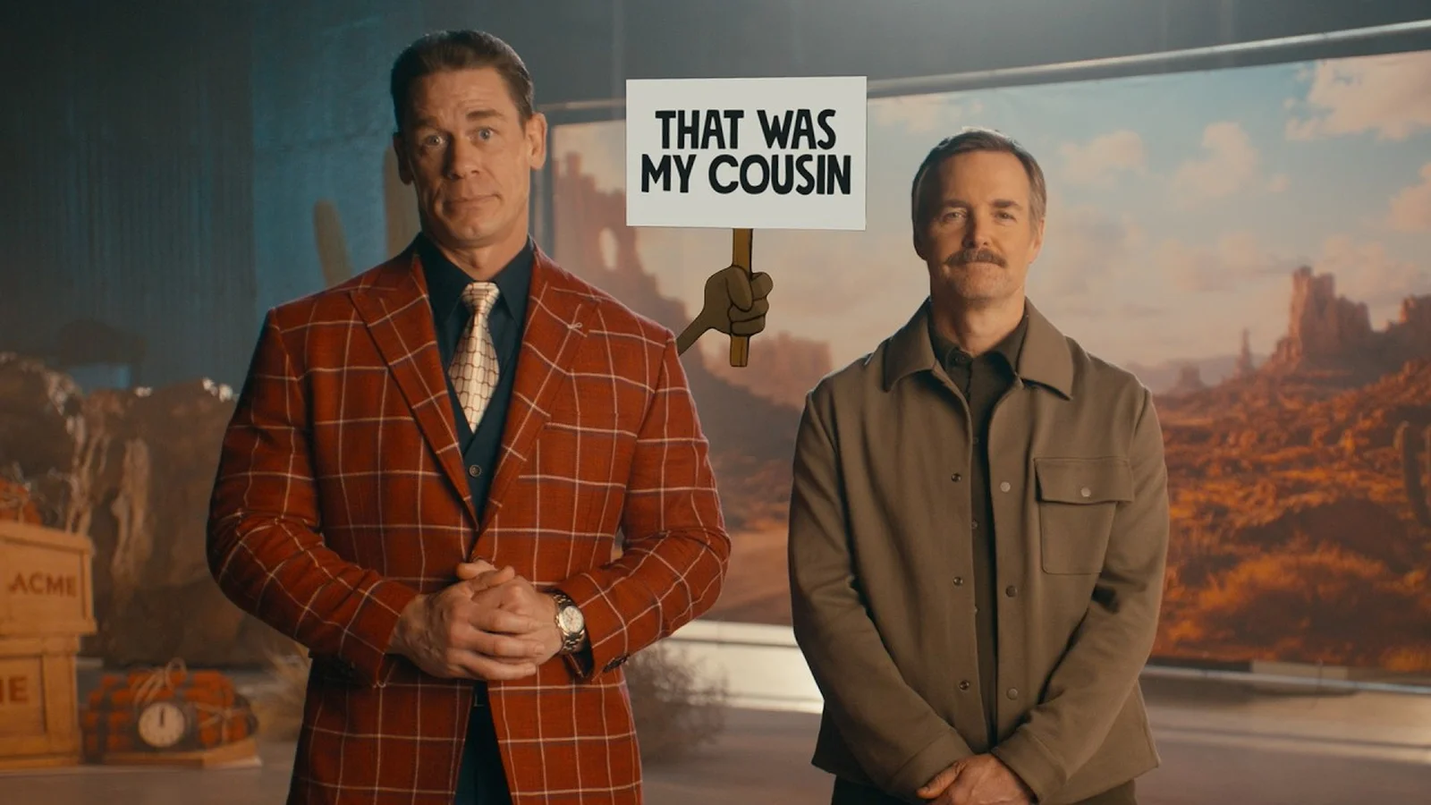 John Cena và Will Forte đứng cạnh tấm biển That was my cousin trong clip quảng bá Coyote vs. Acme