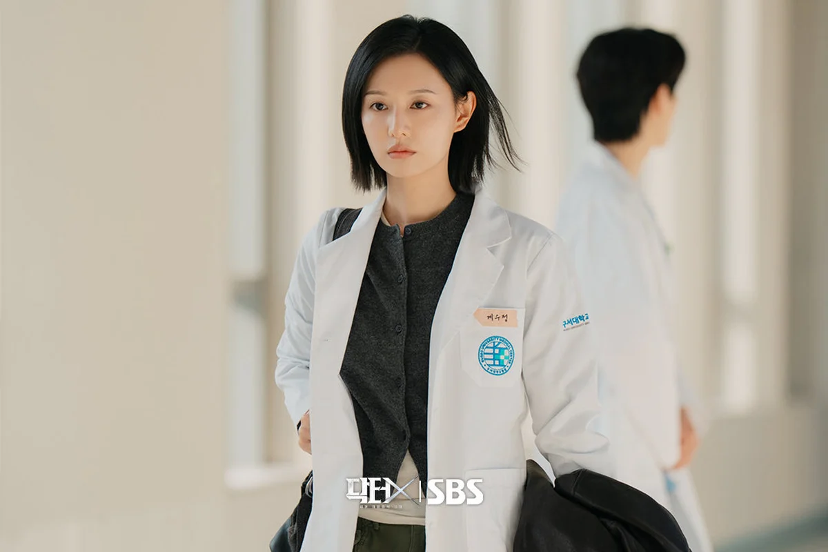 Kim Ji Won mặc áo blouse trắng đi trên hành lang bệnh viện trong phim Doctor X: Mafia in White