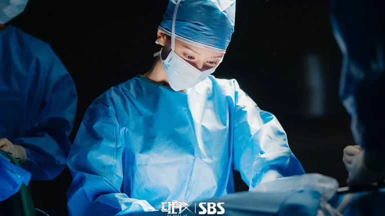 Kim Ji Won đeo khẩu trang, mặc đồ phẫu thuật đứng mổ trong phim Doctor X: Mafia in White của đài SBS