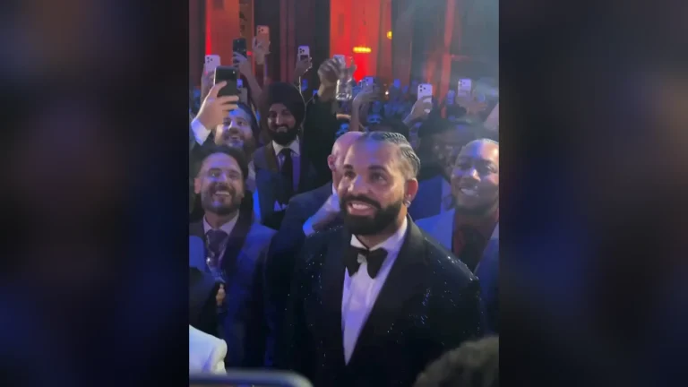 Drake mặc tuxedo đen cười tươi giữa đám đông khách mời giơ điện thoại quay trong tiệc sinh nhật 40 tuổi