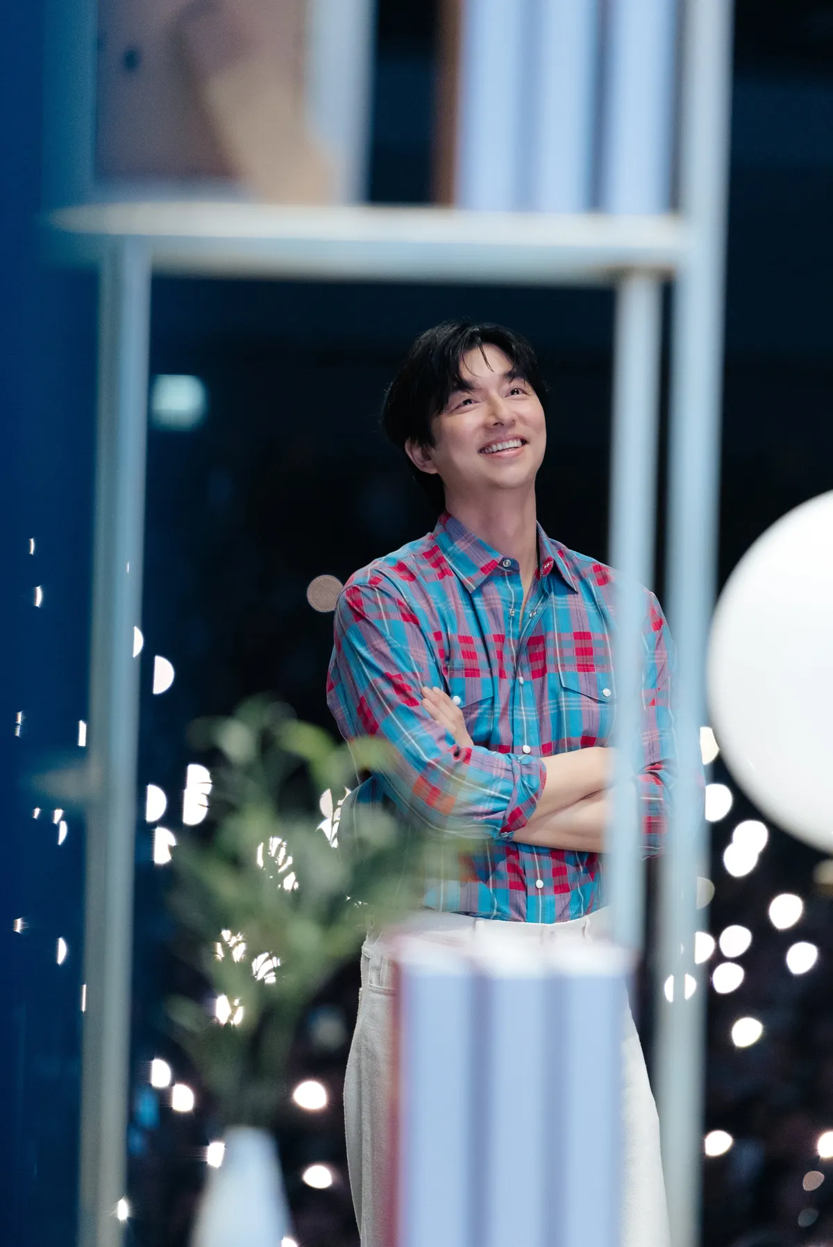 Gong Yoo mặc sơ mi caro hồng xanh, khoanh tay mỉm cười trong fan meeting The Long Take ở Bangkok