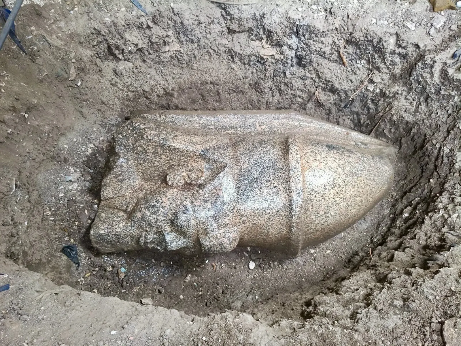 Đầu tượng Ramses II bằng đá granite nằm nghiêng trong hố đất ở làng Behbeit El-Hagar