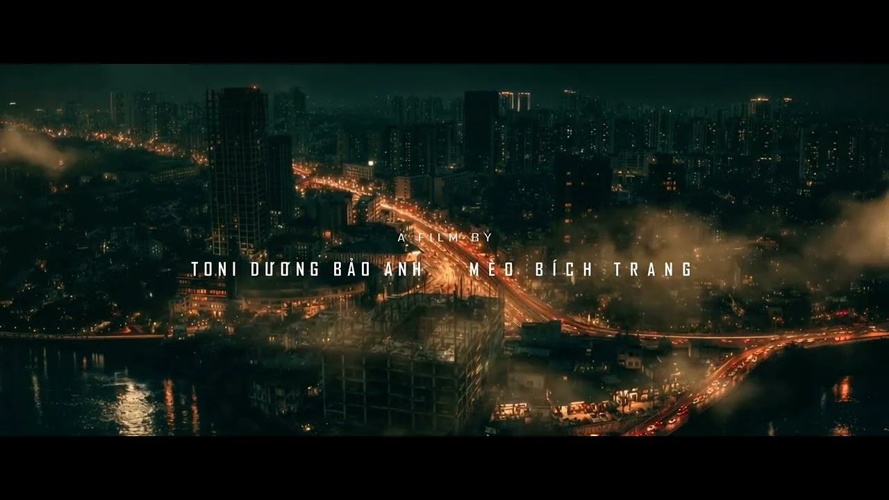 Khung hình trailer Trại buôn người ghi tên đạo diễn Toni Dương Bảo Anh và nhà sản xuất Mèo Bích Trang trên nền thành phố về đêm