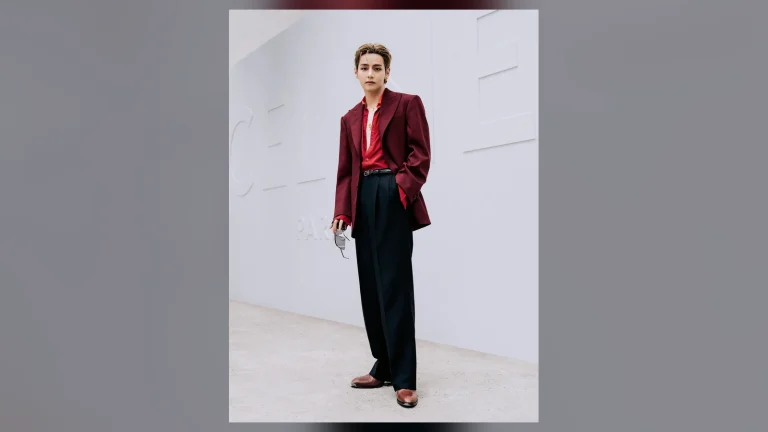 BTS V đứng trước chữ CELINE PARIS, blazer đỏ sẫm, áo đỏ, cầm kính đen