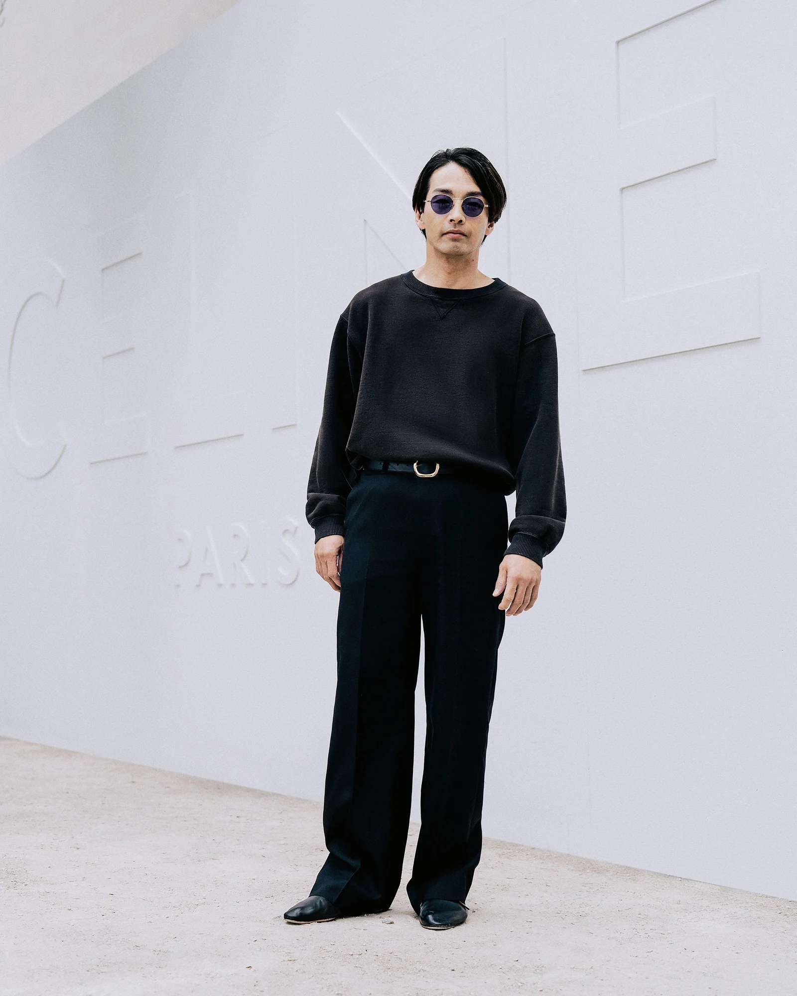 BTS V mặc blazer đỏ sẫm và áo sơ mi đỏ đứng trước chữ CELINE PARIS tại show nam Celine tháng 6